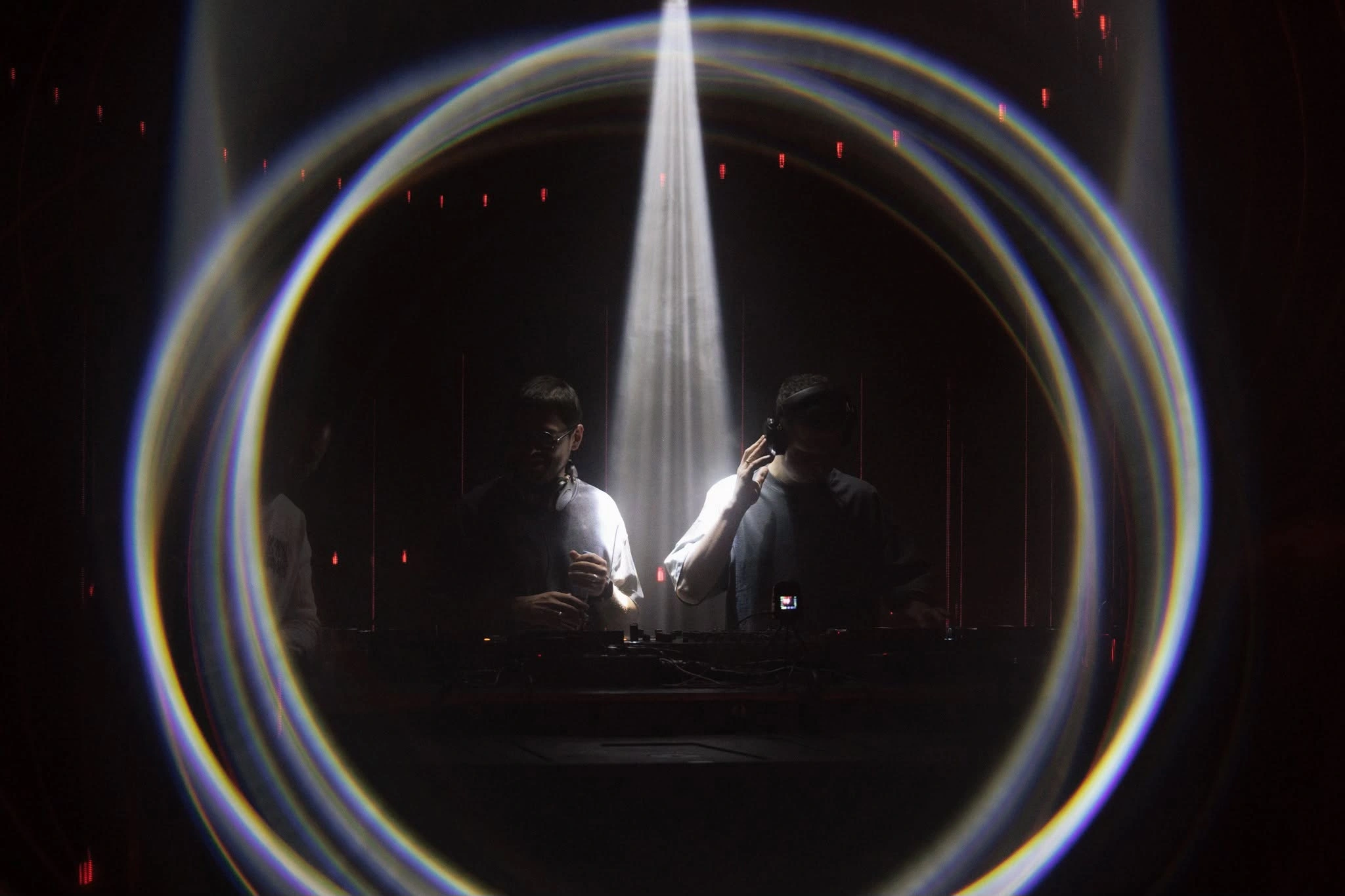 DJs beneath a circular beam of light