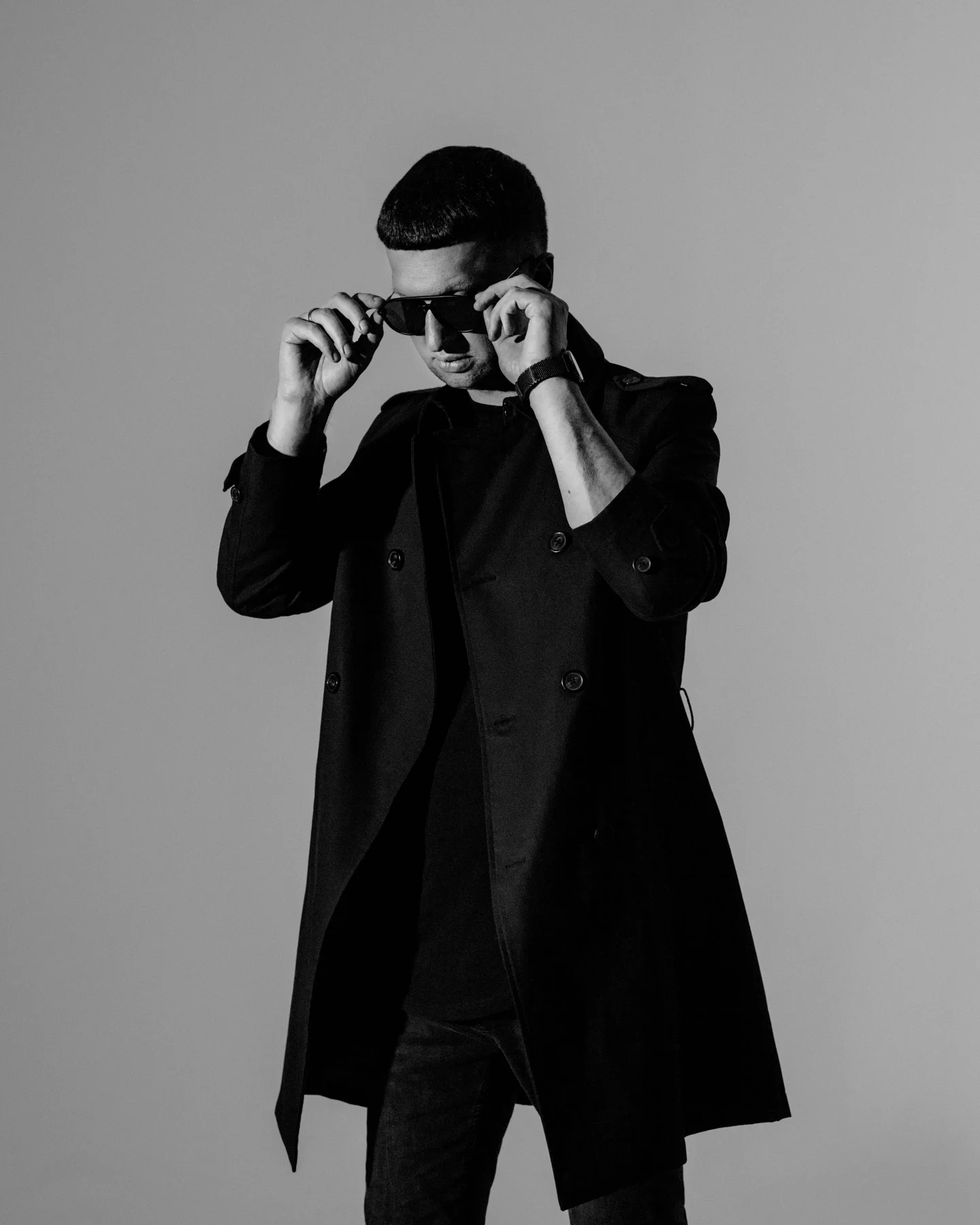 Arnas D in a black suit, adjusting his sunglasses